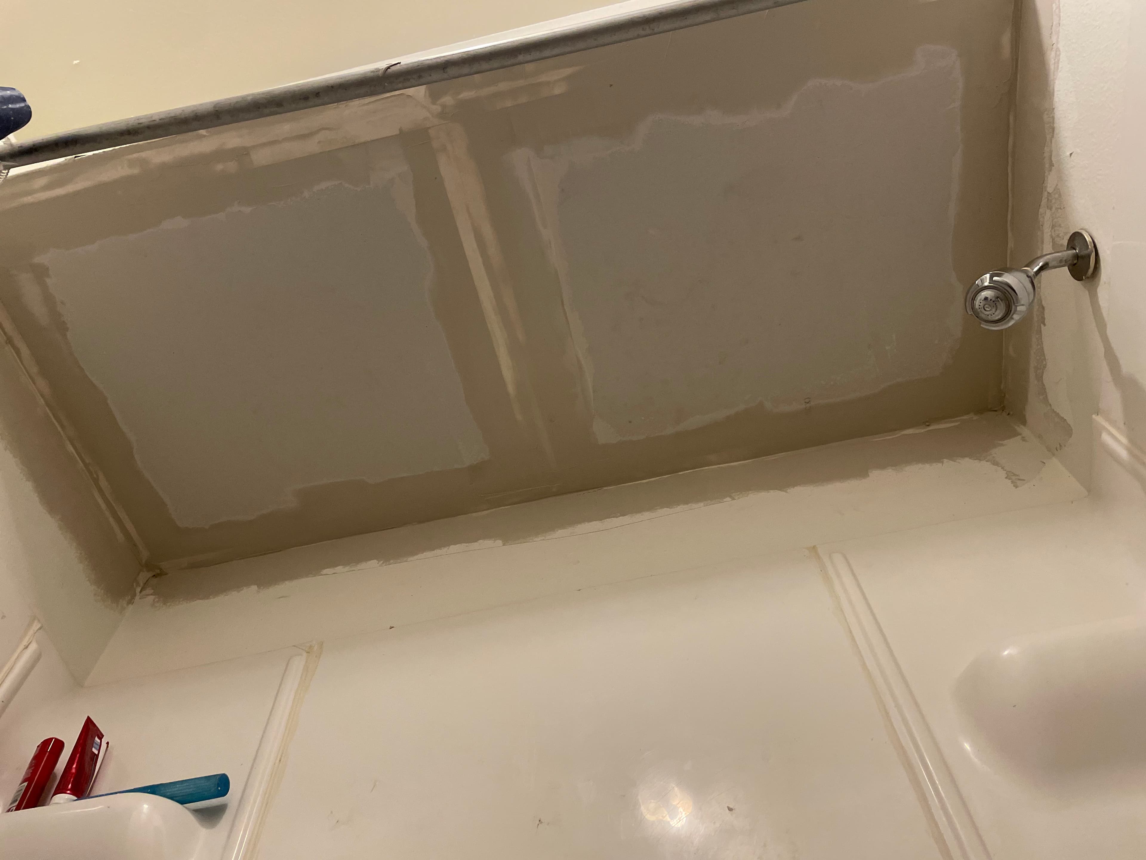 Renovation of a bathroom ceiling with patchy paint and exposed plumbing fixtures.